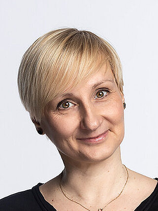 Uśmiechnięta kobieta w średnim wieku z krótkimi blond włosami.